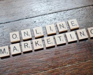 Scrabble tiles arranged to spell 'ONLINE MARKETING' on a wooden table with a textured surface.